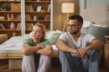 Upset couple ignoring each other after fight in bedroom