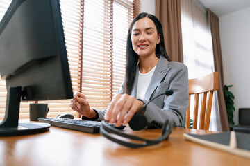 Female call center operator or customer service helpdesk staff working on workspace while talking...