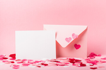 Pink envelope and blank form with paper pink hearts on a pink background. Valentine's day concept.