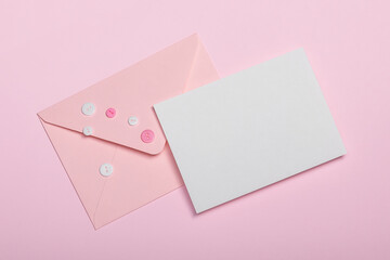 Pink envelope with buttons, empty card on pink background.