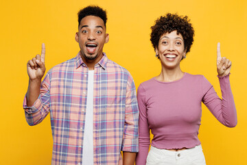 Young smart couple two friend family man woman of African American ethnicity wear purple casual clothes together holding index finger up with great new idea isolated on plain yellow orange background