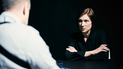 An angry and nervous woman is listening to the male detective's accusations during interrogation