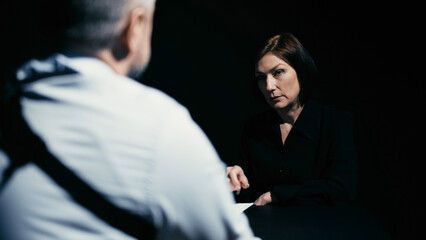 A suspected woman is dictating her testimony to the detective during interrogation