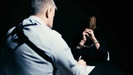 A woman in handcuffs is answering the detective's questions during police interrogation
