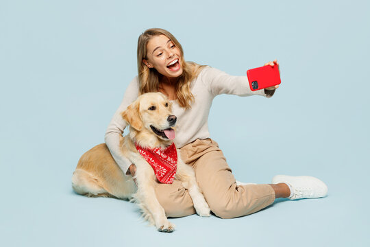 Full body young owner woman with her best friend retriever dog wears casual clothes doing selfie shot on mobile cell phone isolated on plain light blue background studio. Take care about pet concept.