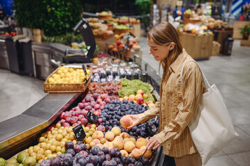 Side view young customer woman wearing casual clothes shopper bag stand in fruit department...