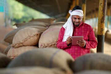 In the grain market, a farmer is using a tablet to view some information.