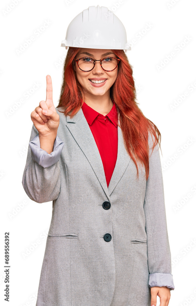 Poster Young redhead woman wearing architect hardhat showing and pointing up with finger number one while smiling confident and happy.