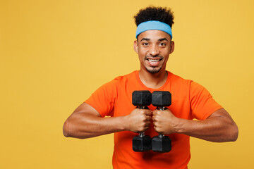 Young fitness trainer instructor sporty man sportsman wears orange t-shirt hold dumbbells hold...
