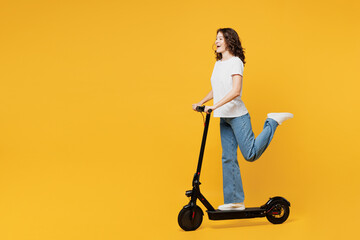 Side profile view young European woman she wear white blank t-shirt casual clothes driving electric scooter look camera isolated on plain yellow orange background studio portrait. Lifestyle concept. - obrazy, fototapety, plakaty