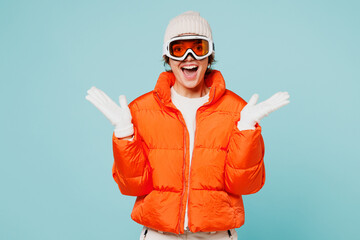 Young excited overjoyed woman wear warm padded windbreaker jacket hat ski goggles mask spread hands...