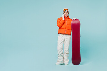 Full body young woman wear warm padded windbreaker jacket ski goggles mask hold snowboard talk...