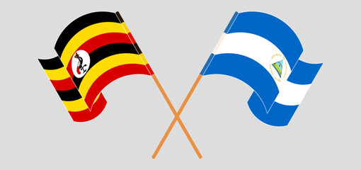 Crossed and waving flags of Uganda and Nicaragua