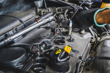 Fototapeta na wymiar Auto mechanic installing a new spark plugs into the engine.