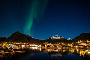 Fototapeta premium bright aurora borealis over a small coastal Sørvågen village on lofoten islands in norway with mountains on background