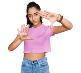 Hispanic teenager girl with dental braces wearing casual clothes doing frame using hands palms and fingers, camera perspective