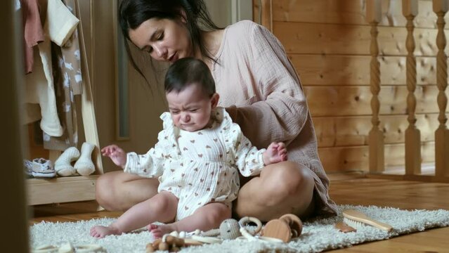 A mother gently dresses her fussy baby, a moment relatable to parents everywhere. It's a blend of love and everyday challenges.