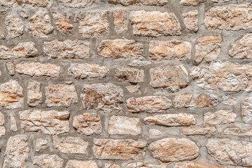 Real vintage texture of antique brick wall with beige brown stones. Element of architecture in the Old Town of Budva, Montenegro. Grunge background with copy space