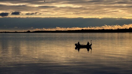 Silhouette of fishermen boat in the morning on the lake.