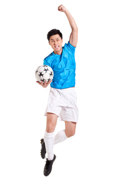 Chinese soccer player holding a ball and jumping in celebration with arm raised into a balled fist