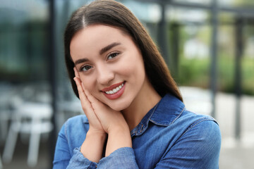 Portrait of beautiful woman outdoors. Attractive lady smiling and looking into camera