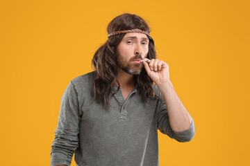 Hippie man smoking cigarette on orange background