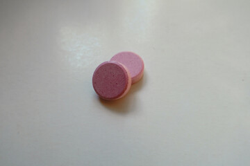 Macro of two big pink oral probiotic tablets