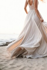 Fototapeta na wymiar A beautiful attractive bride is a woman wearing a fashionable stylish long wedding dress and a veil curling in the wind by the white sandy seashore. Cropped photo.