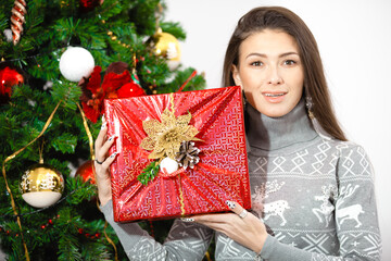 Portrait of happy young woman christmas present boxes in front of christmas tree