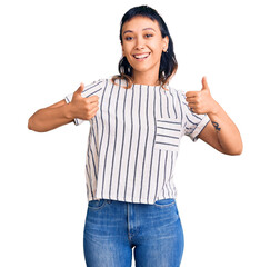 Young woman wearing casual clothes success sign doing positive gesture with hand, thumbs up smiling and happy. cheerful expression and winner gesture.