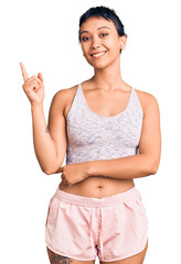 Young woman wearing sportswear smiling happy pointing with hand and finger to the side