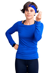 Beautiful young woman with short hair wearing training workout clothes doing italian gesture with hand and fingers confident expression