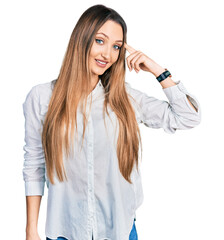 Fototapeta premium Beautiful caucasian woman wearing casual white shirt smiling pointing to head with one finger, great idea or thought, good memory