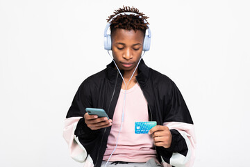 Young concentrated afro american guy wearing modern wireless headphones typing number of credit...