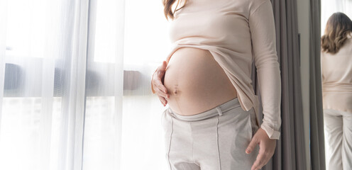 Pregnant woman holds hands on belly touching her baby caring about her health Beautiful happy...