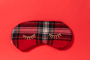Rad tartan sleeping mask with gold eyelashes on a red background