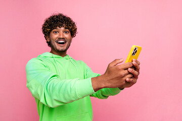 Photo amazed funny guy using smartphone wear green sweatshirt unexpected his blog first million followers isolated on pink color background