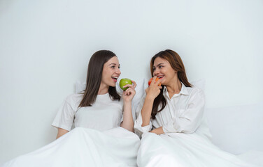 Young Asian lesbian couple sitting on bed during happy resting time Talk and relax in the bedroom.