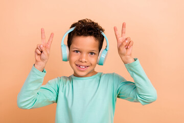 Photo of cute positive boy wear stylish cyan clothes have fun enjoy party listen mp3 plyer v-sign...