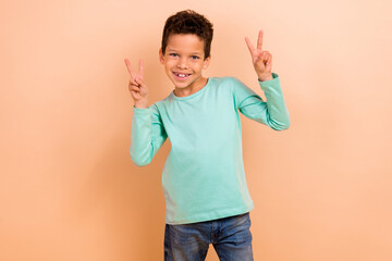 Photo of cheerful nice friendly boy wear stylish collection clothes v-sign sign isolated on beige...