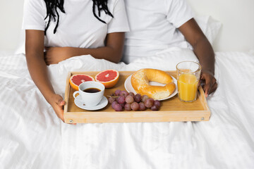 Obraz na płótnie Canvas Top view of tasty beautiful breakfast in bed in the morning. Happy african couple awaking in the morning lying in bed at weekends.