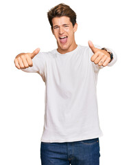 Handsome caucasian man wearing casual white sweater approving doing positive gesture with hand, thumbs up smiling and happy for success. winner gesture.