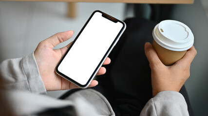 Closeup businesswoman with paper cup in hand using mobile phone at cafe