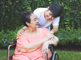 Obraz premium Asian senior woman sitting on wheelchair with her son in the garden.