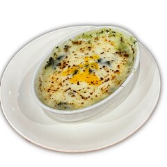 Baked spinach with cheese in a white cup on white backaround.