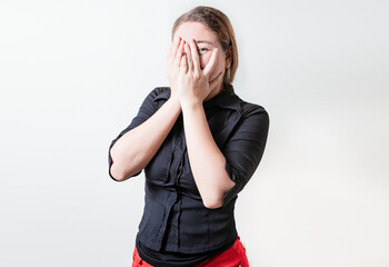 Embarrassed girl covering her face and looking at the camera. Shy girl covering her face and...