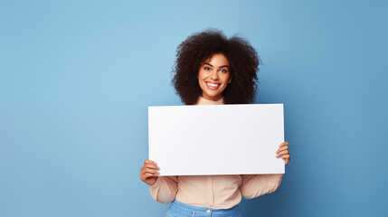 Black woman holding a blank sign and smiling on a plain blue background
