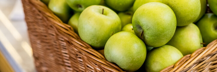 Composition with juicy green apples in wicker basket on table. web banner. Organic fruits on sale...