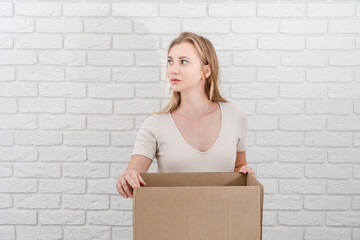 Attractive blonde woman with open cardboard box. Delivering a parcel - obrazy, fototapety, plakaty