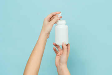 Woman's hand holds white plastic tube. Bottle for pill, capsule or supplement. Product branding...